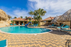 A large pool area with lounge chairs and pool huts.