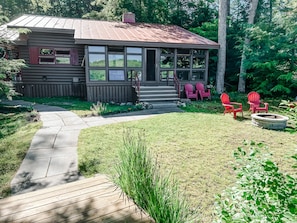 Screened-in/glassed sunroom and firepit with plenty of Adirondack chairs.