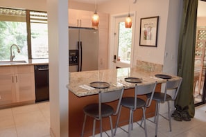 Kitchen features full-size refrigerator, dishwasher, and granite slab counters.