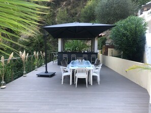 Terrasse attenante à la piscine, avec cuisine d’été, barbecue et four à pizza