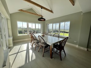 Large dining table for 8 with windows overlooking ocean and mountains.