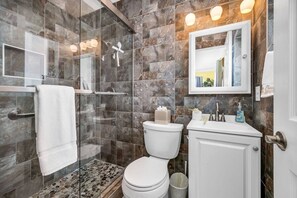 Elegant master en-suite bathrooms with gorgeous dark tiles throughout and a step-in, glass-encased shower.