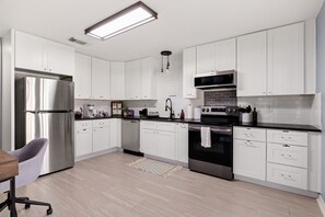 Modern cupboards w/ full range pots and pans, coffee maker, toaster, microwave, fridge, and more.