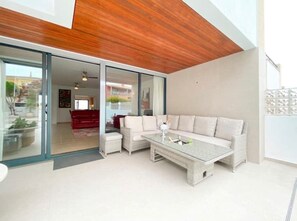 outside covered patio with sofa and coffee table which rises to a Dining table