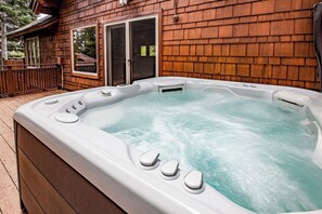 The hot tub on the deck with a stunning forest view.