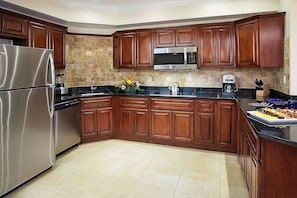 Full kitchen with stove, refrigerator, microwave, coffee maker, kitchenware