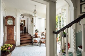 Hall way with original paneling leads to garden. Upright piano in this area.