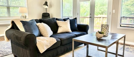 Living room with smart TV, reading nook, desk space, books and games.