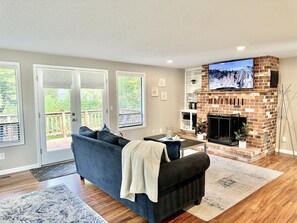 Living room with smart TV, reading nook, desk space, books and games.