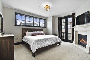Primary bedroom with outdoor patio, TV, and fireplace