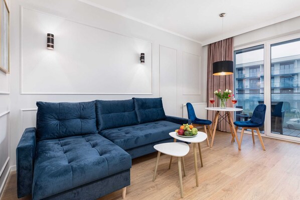 A spacious living room featuring a blue sofa, a coffee table, and large windows providing ample natural light.

