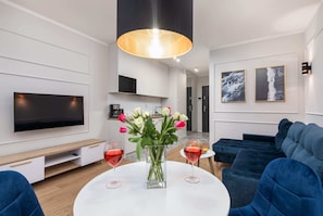 A modern dining space with a round table, elegant chairs, and a decorative pendant lamp.

