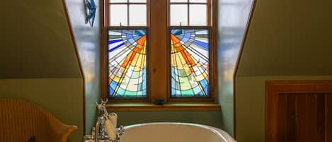 Bright family bathroom with rolltop bath and feature stained glass window