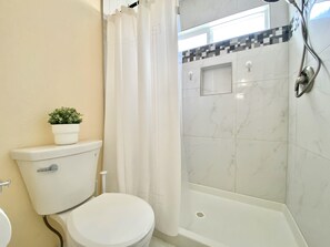 The primary bathroom features a walk-in shower with a handheld showerhead for added convenience. 