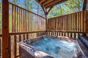 A private outdoor hot tub nestled within a wooden enclosure, surrounded by nature. Perfect for unwinding while taking in the fresh air.