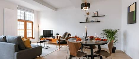 The living/dining room is a spacious and bright room containing a dining table and a comfy seating area.
