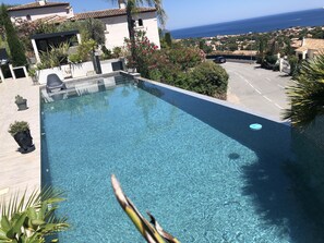 Grande piscine à débordement avec plage et escalier.