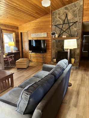 Rocking chair and Vizio Smart TV with soundbar, wood burning stove.