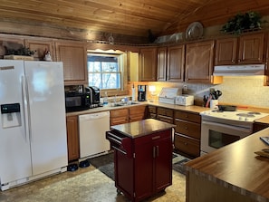 Kitchen equipped with dishwasher, microwave, electric stove and coffee makers.