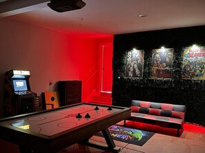 Stylish, retro-themed game room, featuring an air hockey table, vintage arcade machine, and comic wall art. The perfect space for fun, family relaxation, and entertaining guests.