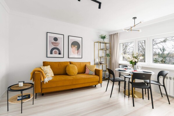 A modern dining area with a mustard-yellow sofa, complemented by a stylish table and chairs.