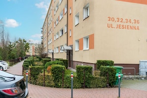 An exterior view of the residential building, showcasing its neat surroundings and parking area.