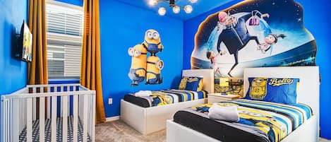 Playful themed kids' room with twin beds, vibrant decor, and a crib.