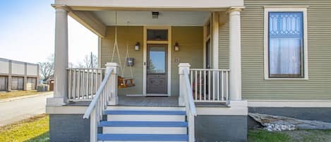 Front porch has a porch swing and a pair of Adirondack chairs.