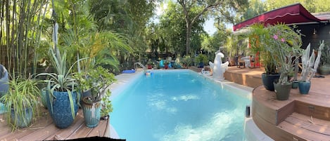 Panorama view of pool and backyard sitting area with firepit.