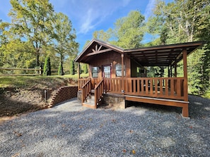 Property side view of cabin. Cabin sits below grade