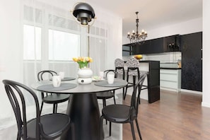 A modern dining area with black chairs, a round table, and bright natural light from large windows.