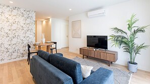 Dining/living area with a sofa, flat screen TV and AC unit for maximum comfort. #lovelystay #comfort #AC