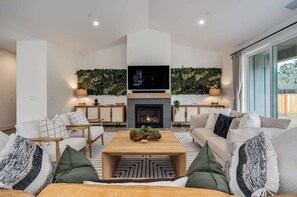 Living area with a 65 inch smart TV, SONOS surround sound system, gas fire place, board games. 