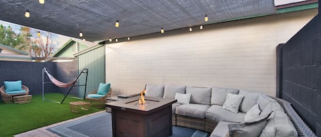 String lights overhead with ample seating to sit around the fire pit and relax! 