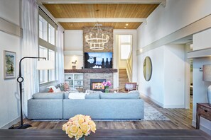 Oversized great room with vaulted ceilings, fireplace, Sonos, and 75" TV.
