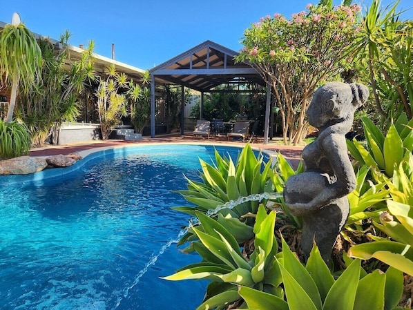Bali style solar heated pool and patio area with sun loungers, dining table and chairs