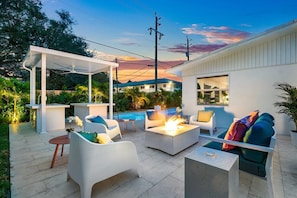 Enjoy the warm Florida climate around the firepit on the outdoor lounge, sitting next to an outdoor bar area overlooking the pool and luxury hot tub.