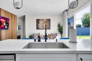Bright kitchen sink area with a modern faucet, dish and hand soap dispensers