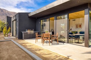 Large patio with an outdoor dining table and BBQ grill outside the living room.