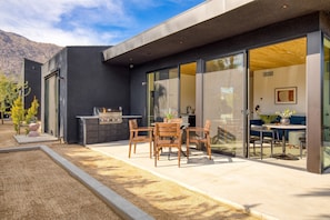 Huge sliding doors connect the living and kitchen area to an outdoor patio with al fresco dining and a BBQ grill.