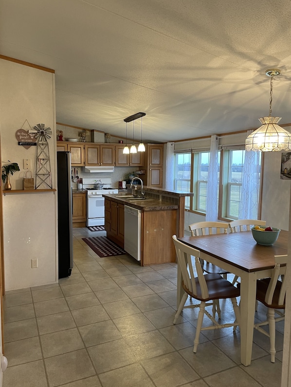 Spacious open kitchen with bar stools and farm table that seats six.