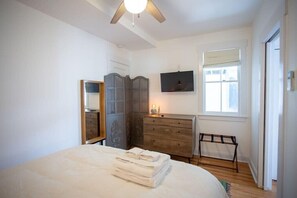 Bedroom with chest of drawers, luggage rack, full length mirror, and streaming tv