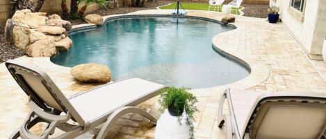 Back yard Oasis, heated pool and waterfall with sunning deck and green turf area