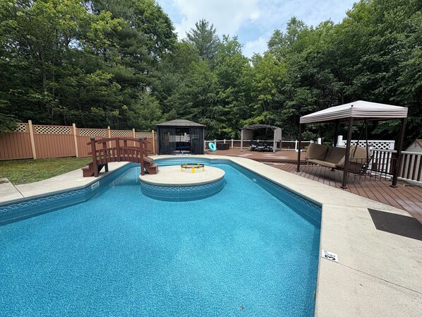 Private pool with centre island with wraparound deck , lounge chairs.