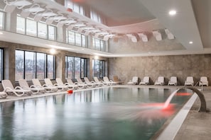 A luxurious indoor pool with elegant lighting and lounge chairs.
