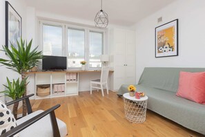 An open living and dining space with a comfortable gray sofa, houseplants, and a cheerful atmosphere.
