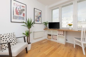 A bright living area featuring a dining table, patterned armchair, and lots of natural light.
