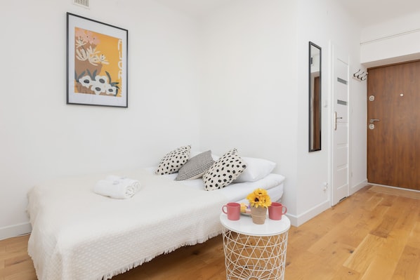 A cozy bedroom with a neatly made bed, stylish wall art, and a wicker bedside table.
