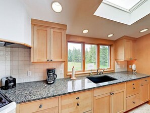 Granite countertops with large farm kitchen sink with a view of one of the fields.