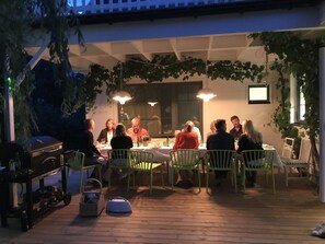 Stort matbord på terrass under tak med vindruvor
